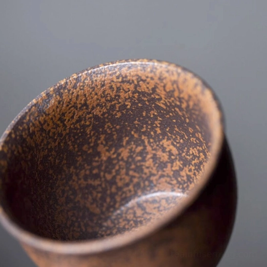 Iron rust glaze tea cup held in hand to show ergonomic size