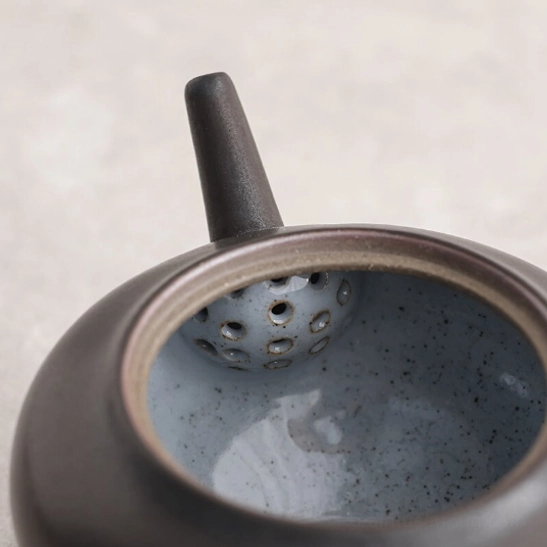 black ceramic teapot held in hand to show compact size