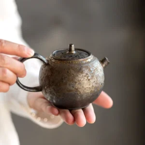 200ml ceramic teapot with infuser held in hand for size reference