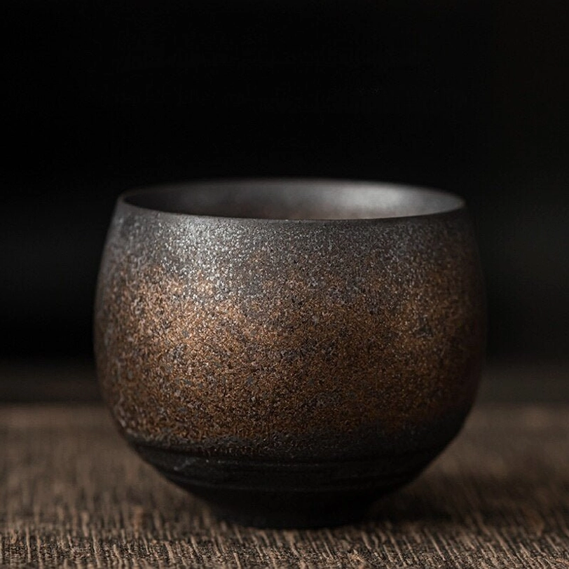 black brown gradient Chinese clay tea cup held in hand
