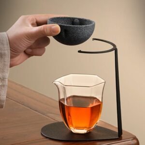 Black textured ceramic tea strainer displayed on black metal stand