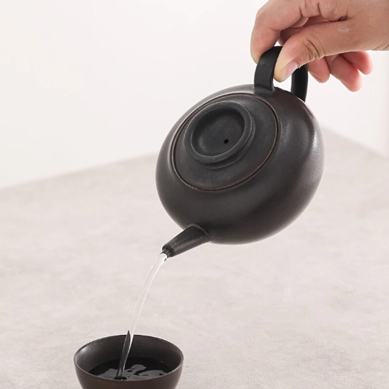 interior side view of black ceramic teapot with infuser