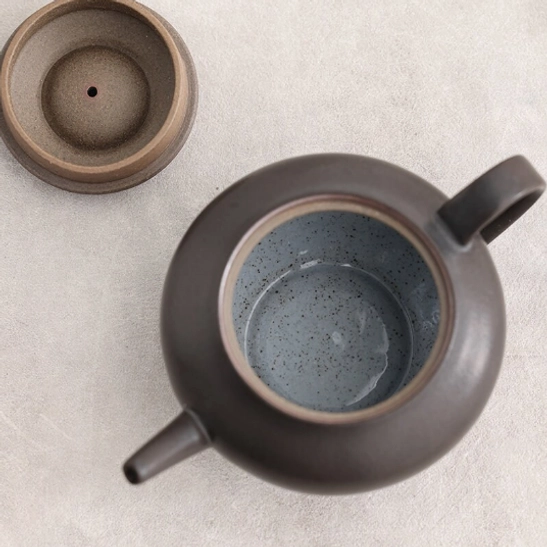 demonstration of steady pouring from black ceramic teapot