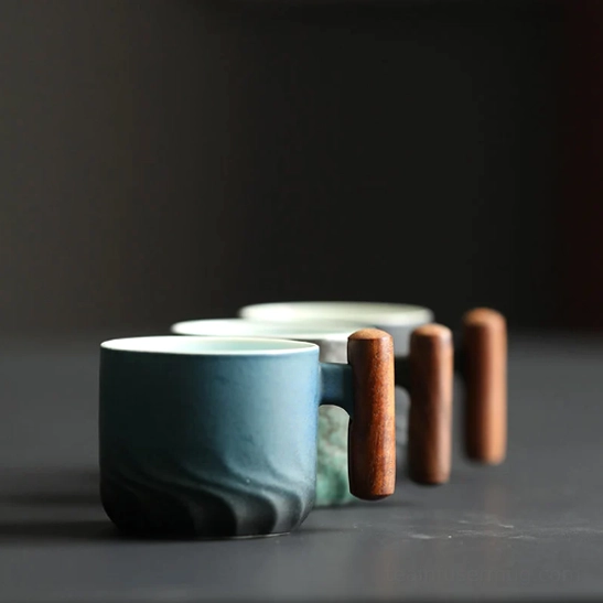Black matte ceramic tea cup with wooden handle side view