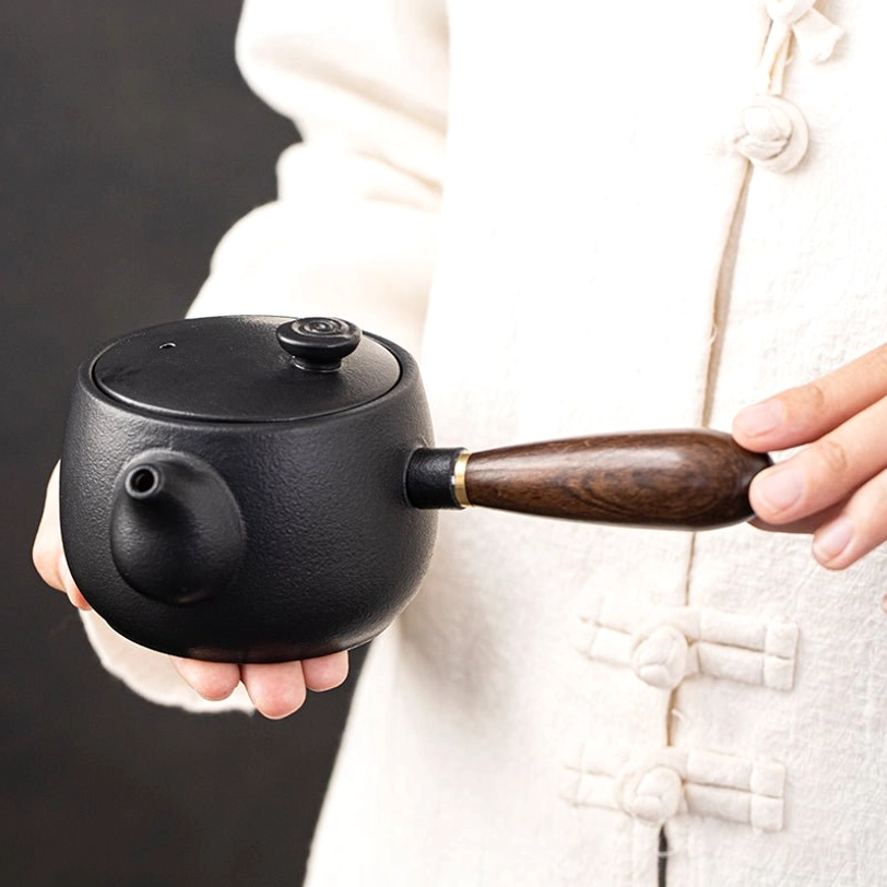 close up of landscape and bird art on black ceramic side handle teapot