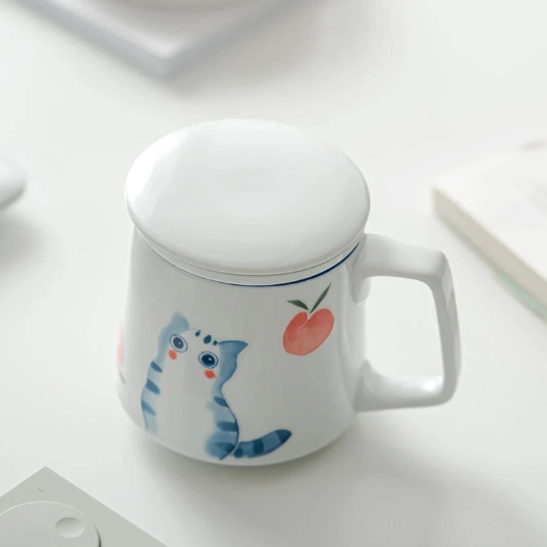 close up of blue cat and red peach pattern on white ceramic tea infuser mug
