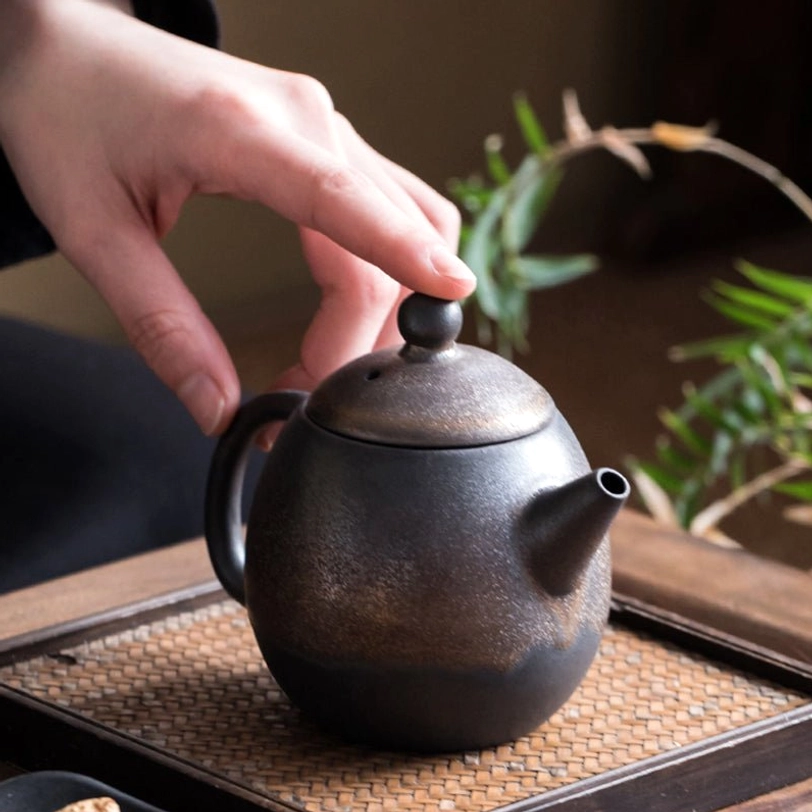 bronze ceramic teapot with infuser standing on dark display background 160ml