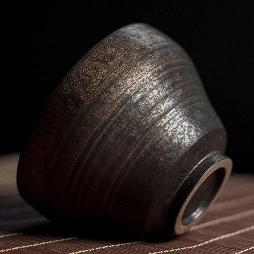 close up of textured bronze gilded clay tea cup surface