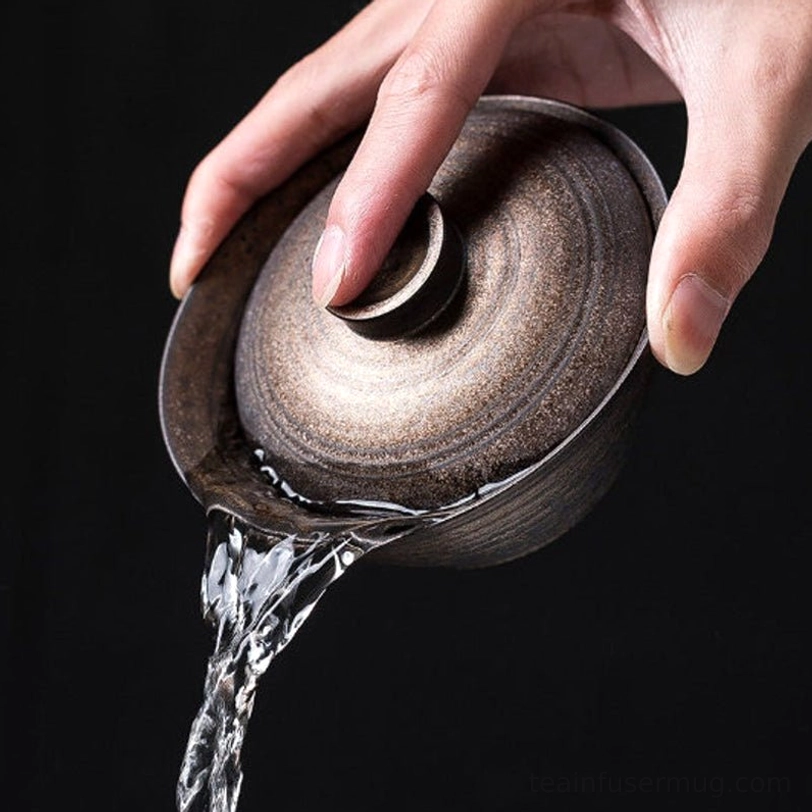 Antique bronze Chinese gaiwan tea cup being held for demonstration