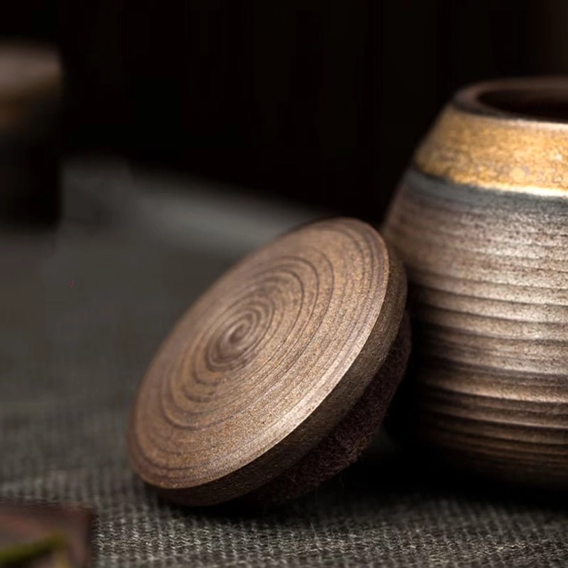 side view of textured brown ceramic tea storage canister with gold accent