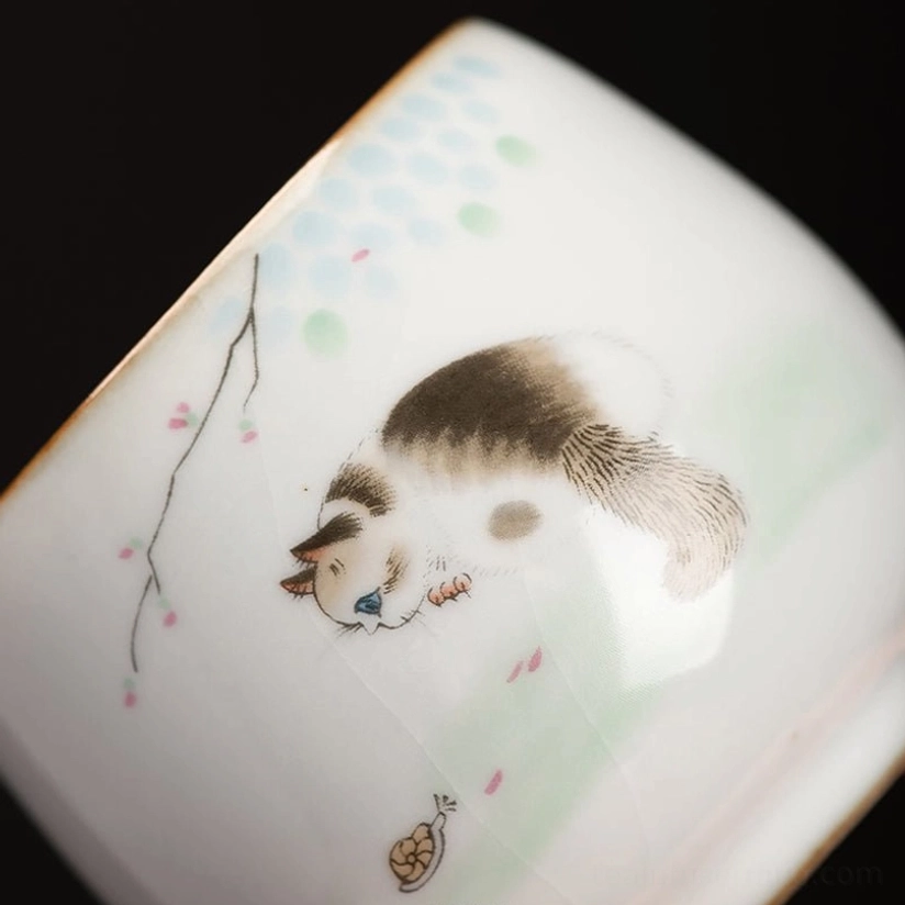 close up of gold rim on cat motif chinese ceramic tea cup
