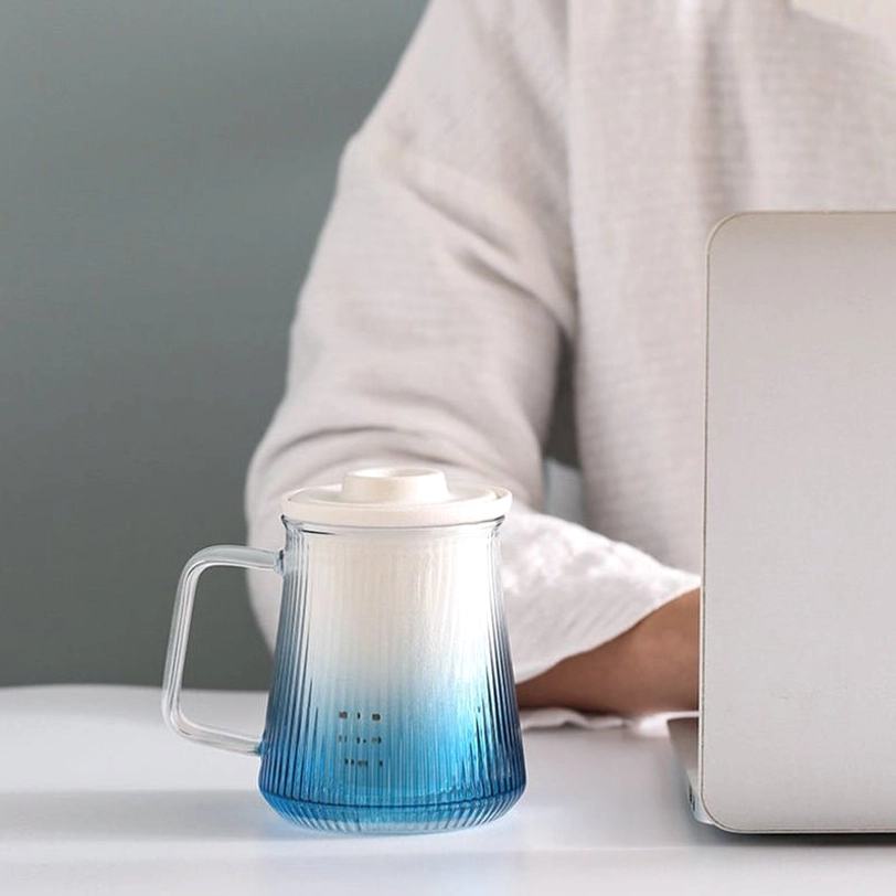 ceramic tea infuser resting on lid of blue gradient glass tea mug
