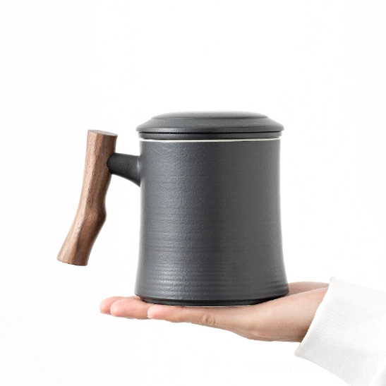Disassembled ceramic tea mug with wooden handle showing infuser and lid