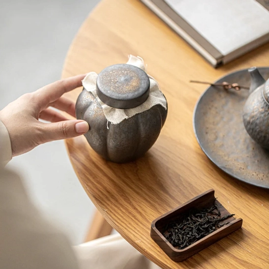 Ceramic tea storage canister displayed on a minimalist wooden tea table