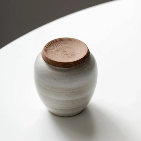 sealed white ceramic tea storage canister standing on natural wood surface