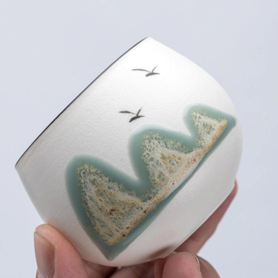 chinese ceramic tea cup with mountain landscape held in hand