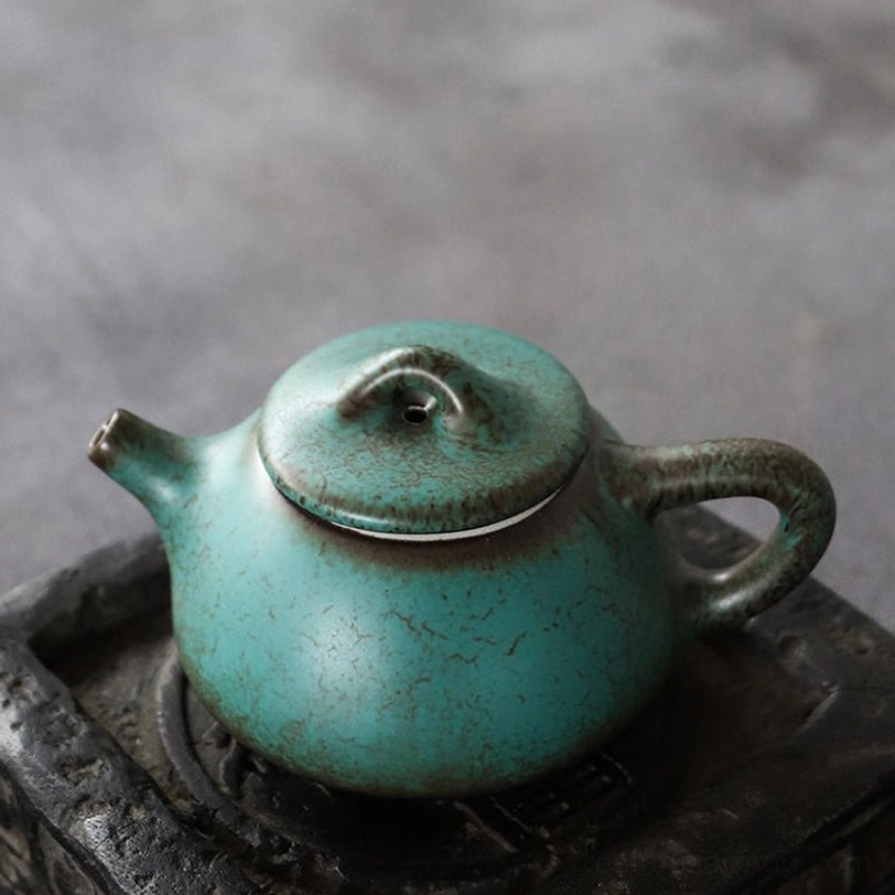 close up view of built-in infuser filter inside turquoise ceramic teapot