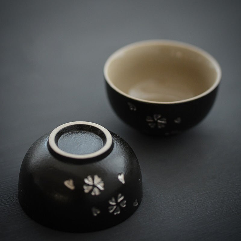 close up of silver sakura pattern on black ceramic japanese tea cup