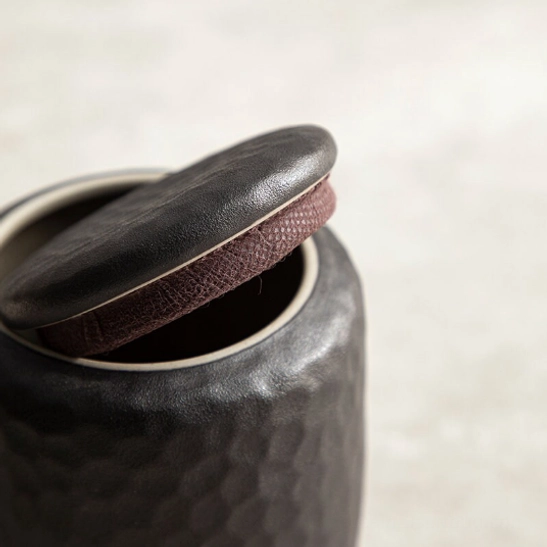Closed black ceramic tea storage canister lifestyle shot on tea table
