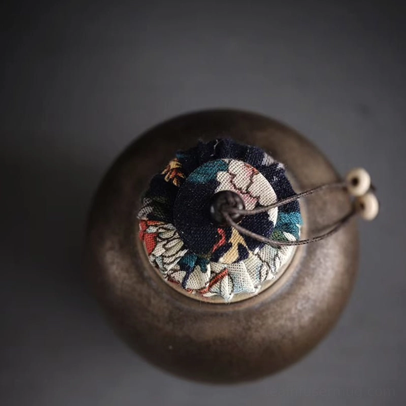 close up of patterned cloth lid on ceramic tea storage canister