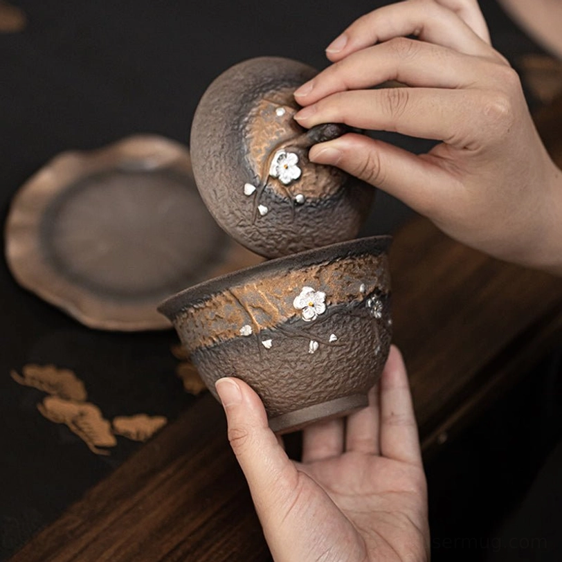Close up of embossed plum blossom decoration on rustic ceramic gaiwan tea cup