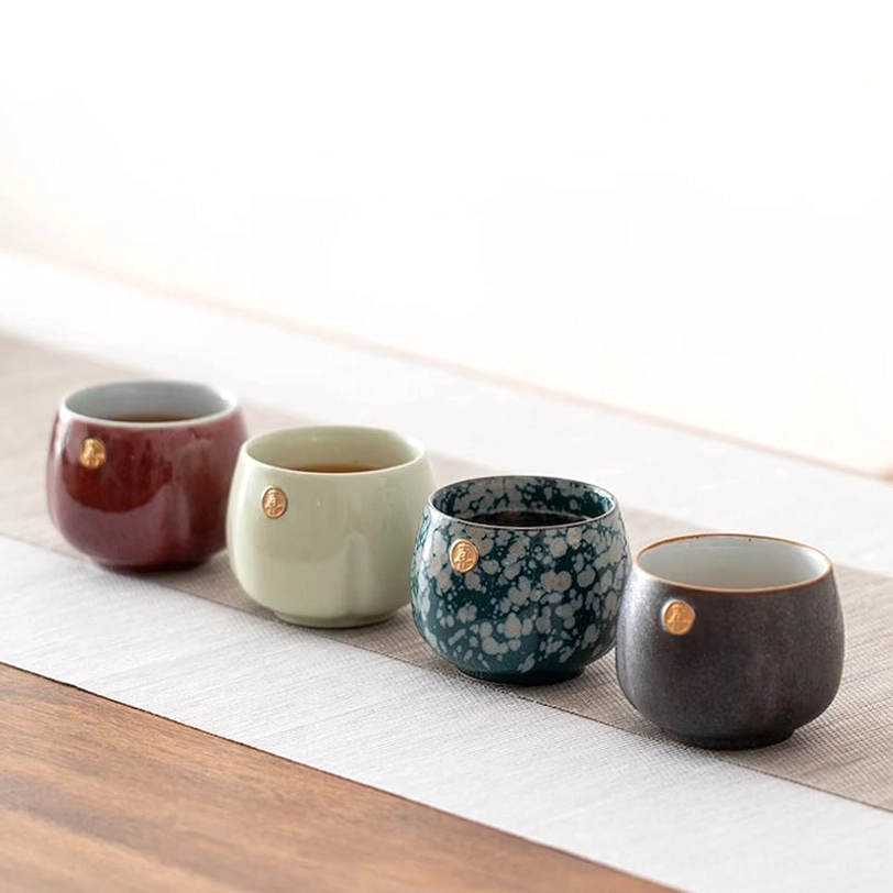 four mixed color chinese ceramic tea cups next to gift box