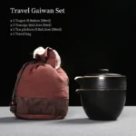 Full 6 piece black and white ceramic travel tea set displayed with brown carry bag