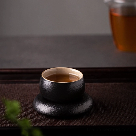 Full set of black Japanese tea cup and matching saucer laid flat