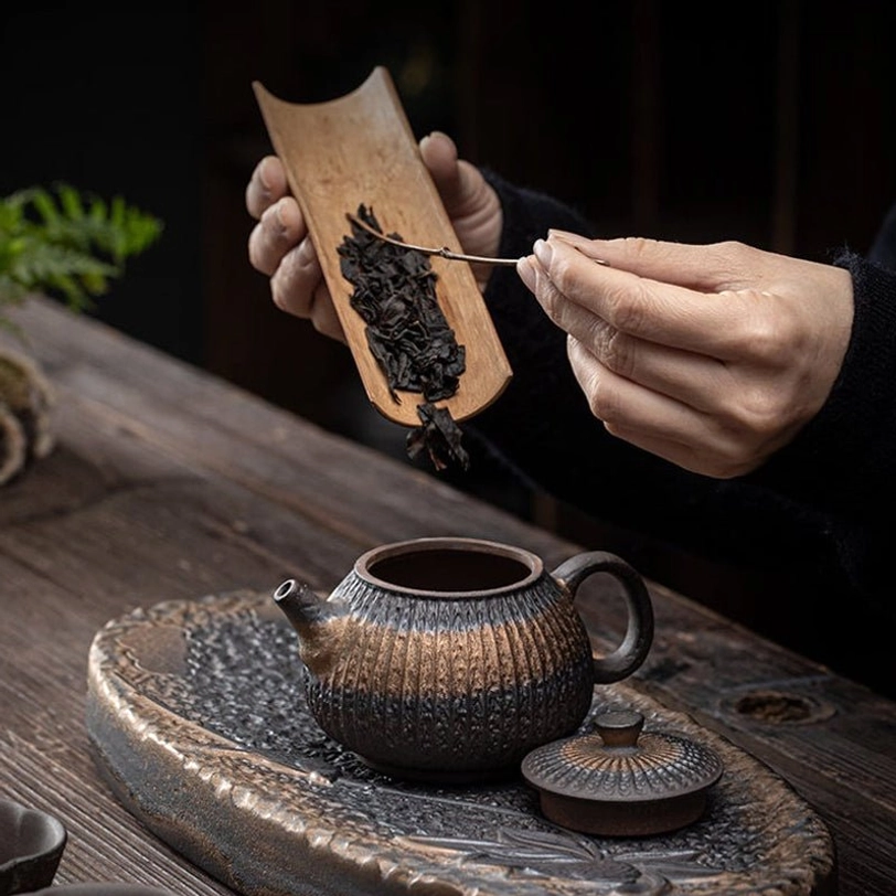 gilded iron glaze teapot on wooden tea table with matching tea set