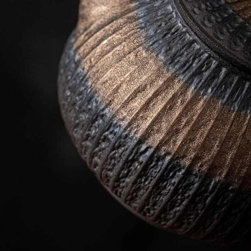 side angle view of gilded iron glaze ceramic teapot with infuser