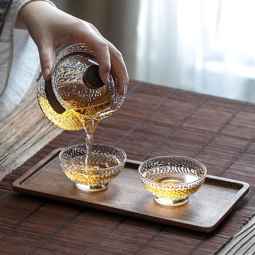 hammered glass gaiwan with wood handle showing smooth pour of tea