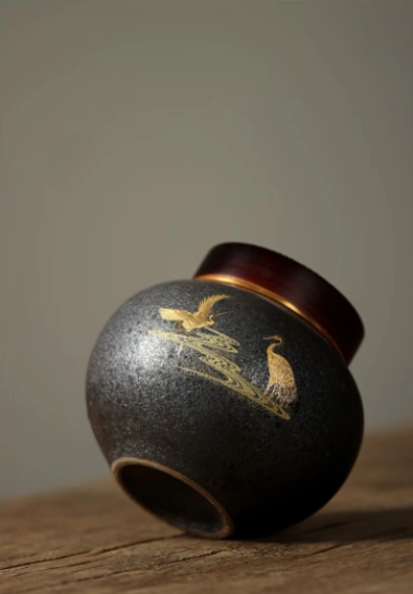 Close-up of golden crane and water motif on ceramic tea storage canister