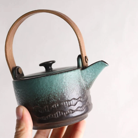 green brown gradient ceramic teapot with wooden handle on neutral background