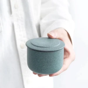 green sealed ceramic tea storage canister hand held view