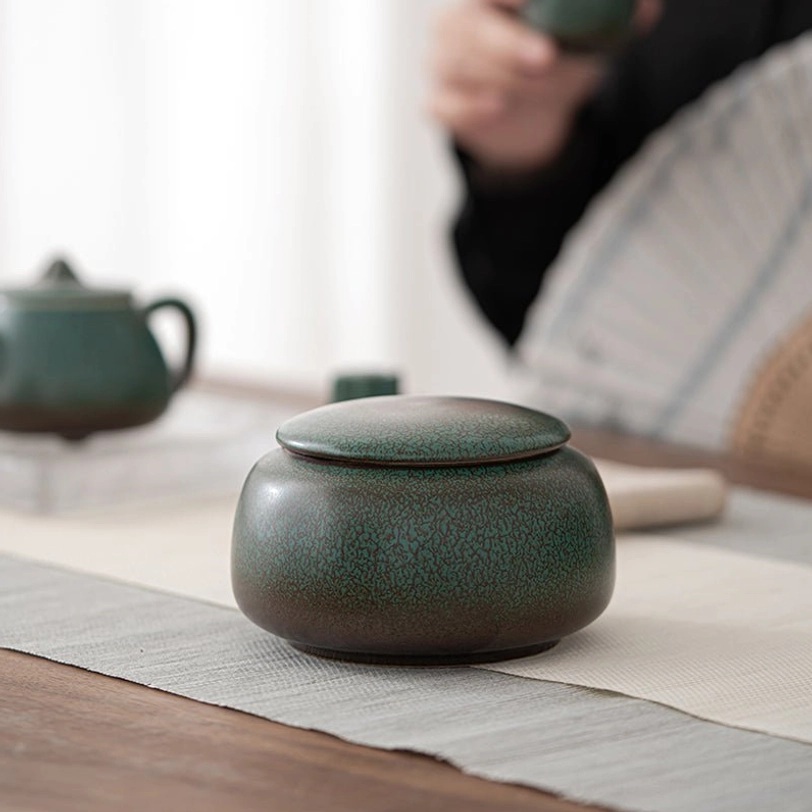 hand holding open ceramic tea storage canister