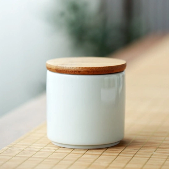 Hand holding small ceramic tea storage jar showing portable size