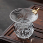 handblown transparent glass tea strainer with gold decorative accents and fine stainless steel filter