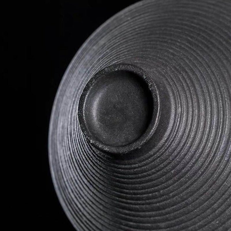 Handcrafted black clay gongfu tea cups set on natural wooden background