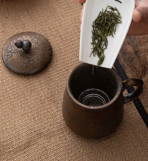 close up of rustic mottled kiln change glaze on ceramic tea infuser mug
