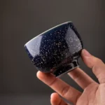 hand holding kiln transformed chinese tea cup showing glaze texture