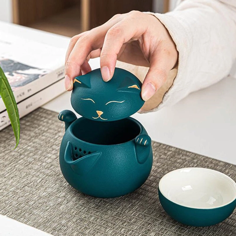 lucky cat ceramic travel tea set with teapot poured into a tea cup