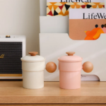 full product view of hand made beige ceramic tea cup with strainer lid and wood handle