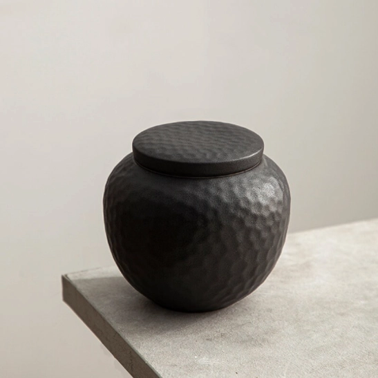 Black ceramic tea storage canister opened with loose tea inside
