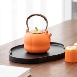 orange persimmon ceramic teapot set on black tea tray
