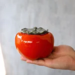 persimmon shaped ceramic tea caddy held in hand loose leaf tea storage