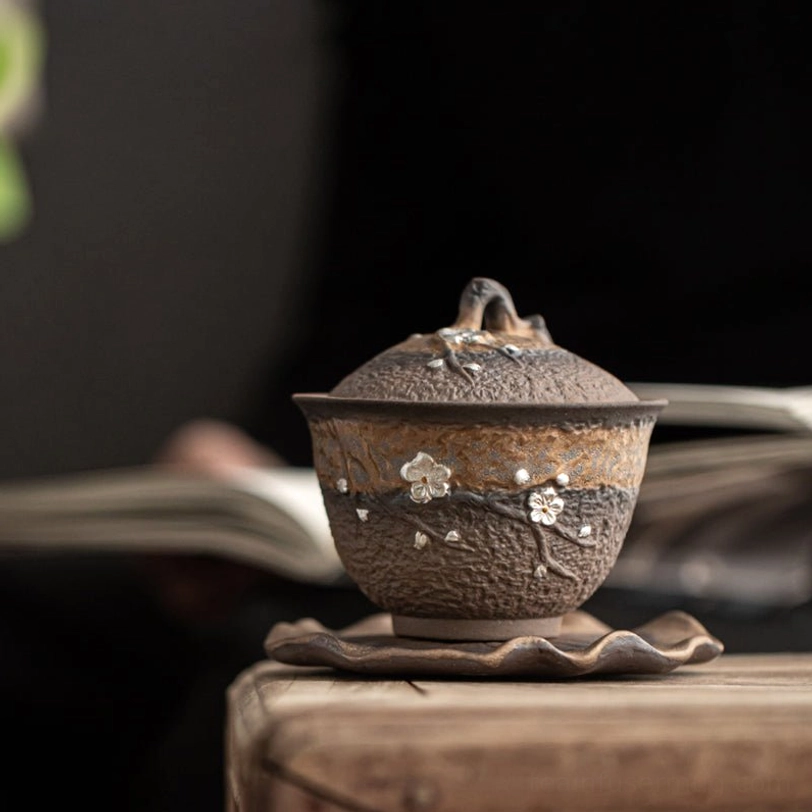 Embossed plum blossom stem detail on rustic ceramic gaiwan tea cup