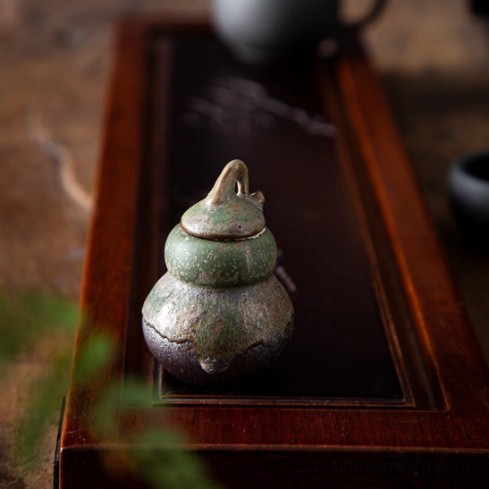 pouring loose tea leaves from the gourd ceramic tea storage canister