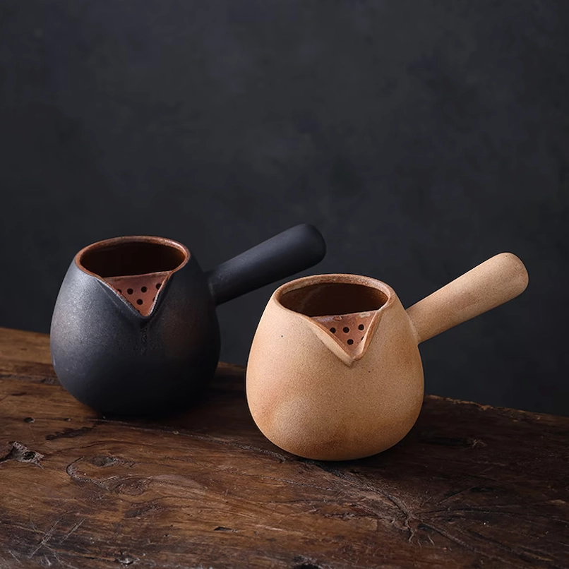 pouring clear tea from ceramic kyusu teapot with built-in infuser