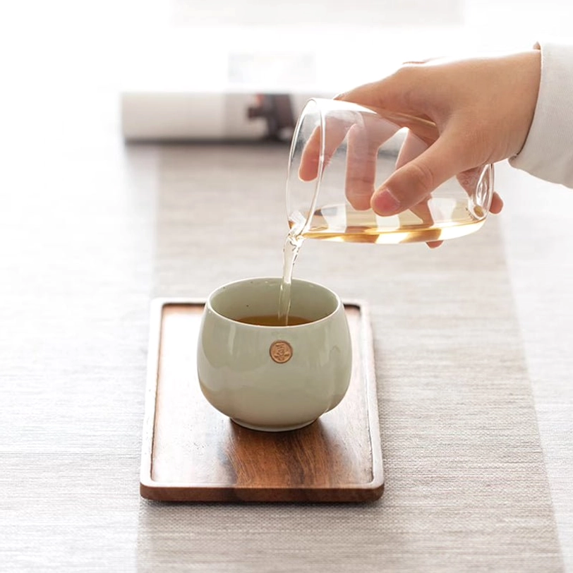 pouring hot tea into a chinese ceramic tea cup from a gongdao bei