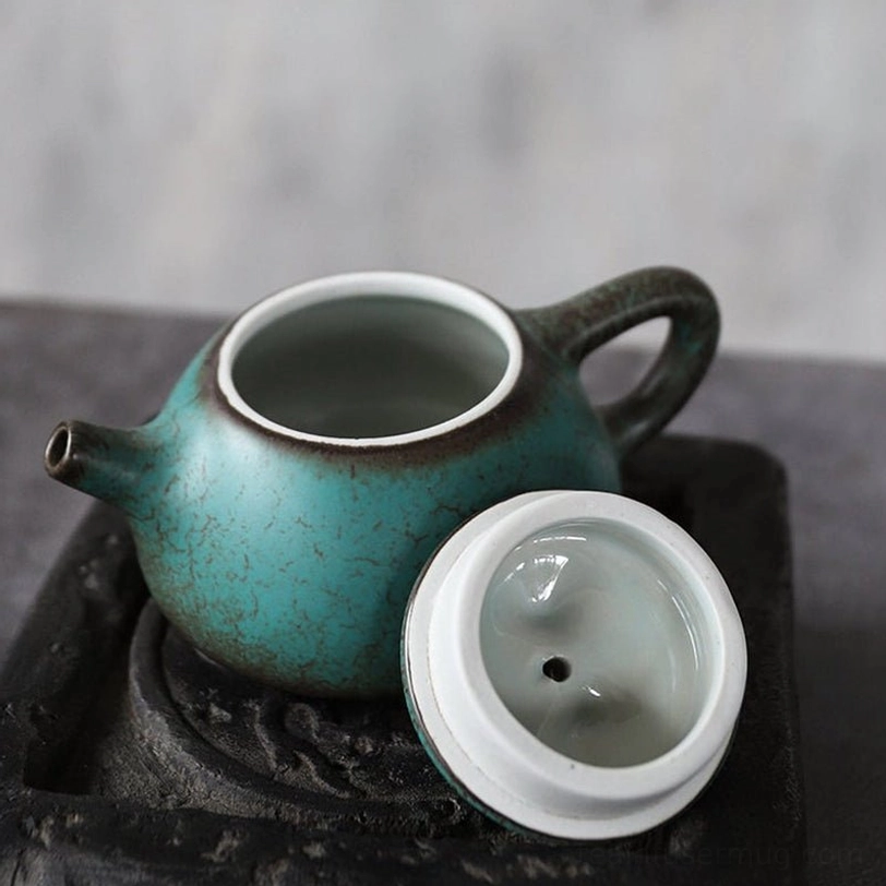 profile view of turquoise ceramic teapot showing spout and handle